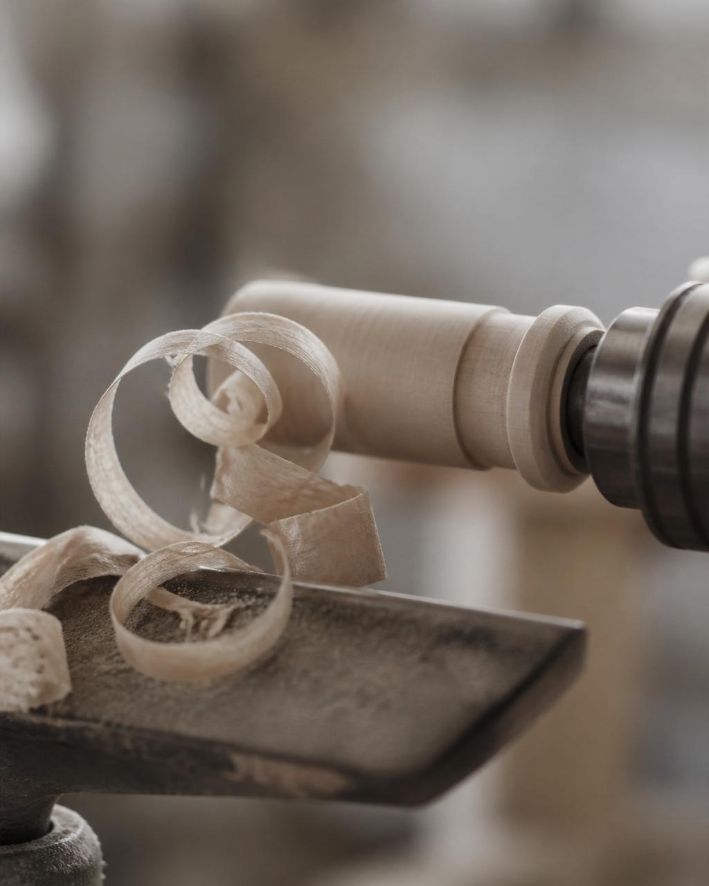Wood shavings curling from a pen turning lathe